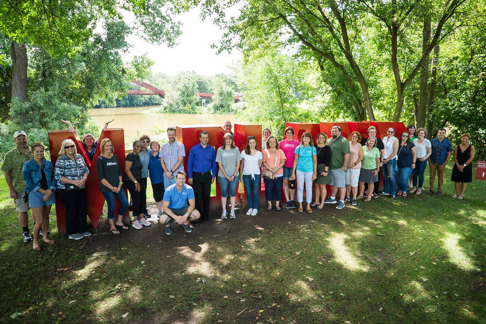 Members of the Midland Area Community Foundation post next to a large "Midland" sign